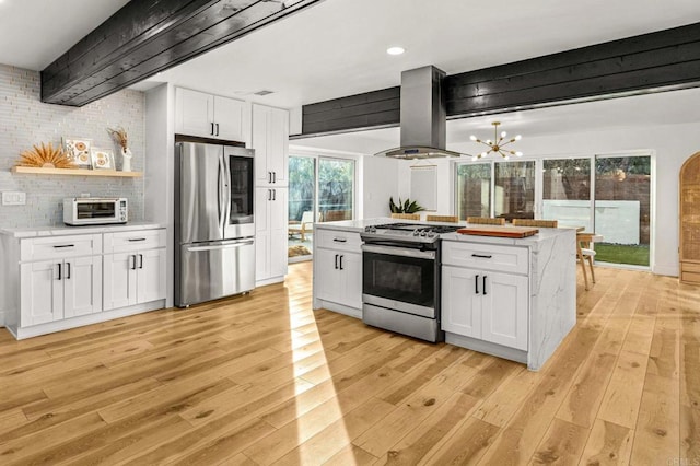 kitchen featuring appliances with stainless steel finishes, white cabinetry, island exhaust hood, decorative backsplash, and light wood-type flooring