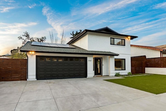 view of front of property with a garage, a yard, and solar panels