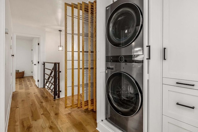 laundry room featuring light hardwood / wood-style floors and stacked washer and clothes dryer