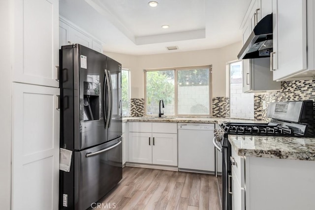 kitchen featuring appliances with stainless steel finishes, white cabinetry, backsplash, a raised ceiling, and light stone countertops