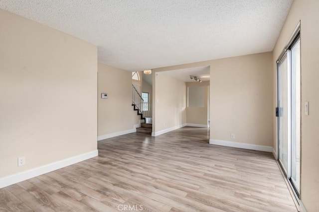 unfurnished room with a textured ceiling and light wood-type flooring