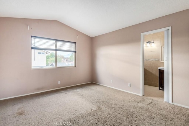 spare room with light carpet and vaulted ceiling