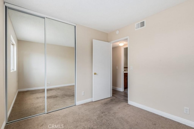 unfurnished bedroom featuring light carpet and a closet