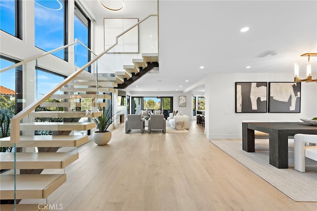 foyer entrance with light wood-type flooring, a high ceiling, and a chandelier