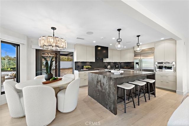 kitchen featuring white cabinetry, pendant lighting, a kitchen island with sink, and stainless steel appliances