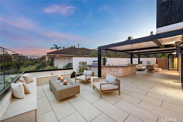 patio terrace at dusk with exterior kitchen and an outdoor fire pit