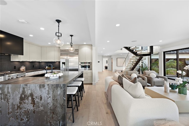 kitchen featuring appliances with stainless steel finishes, pendant lighting, sink, white cabinetry, and a kitchen bar