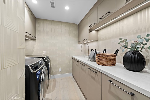 kitchen with washing machine and clothes dryer, sink, gray cabinetry, and light hardwood / wood-style flooring