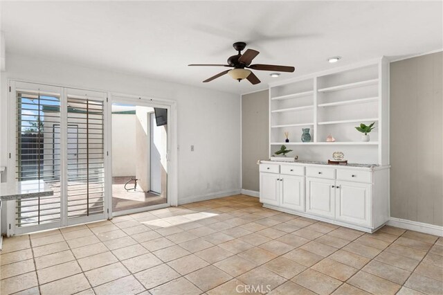 tiled empty room with ceiling fan and built in features