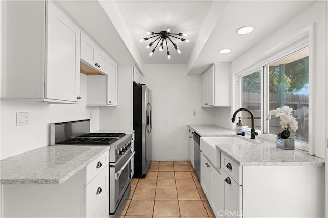 kitchen featuring white cabinetry, sink, light tile patterned floors, and appliances with stainless steel finishes