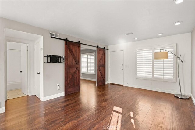 unfurnished living room with dark hardwood / wood-style floors and a barn door