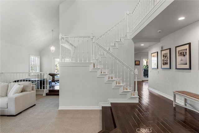 stairs with hardwood / wood-style flooring, a chandelier, and high vaulted ceiling