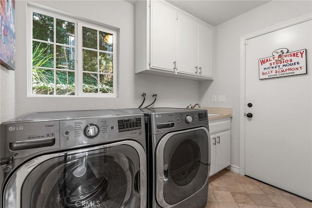 laundry area with cabinets, washing machine and dryer, and sink