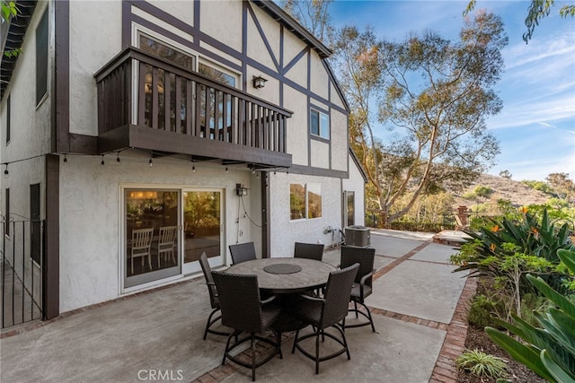 view of patio featuring a mountain view, central AC unit, and a balcony