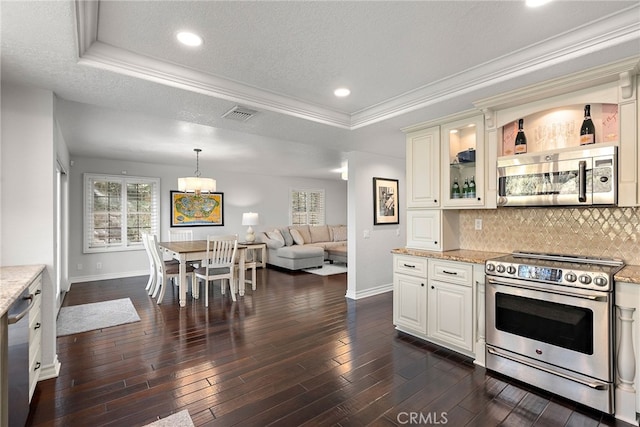 kitchen featuring appliances with stainless steel finishes, white cabinets, light stone counters, a raised ceiling, and dark wood-type flooring