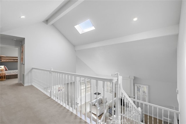 corridor with carpet floors and vaulted ceiling with skylight