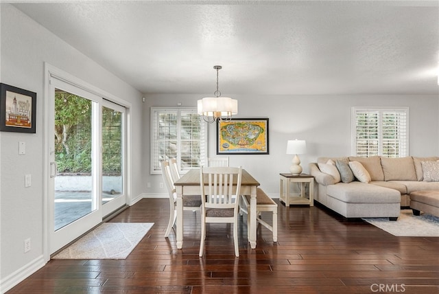 dining space featuring dark hardwood / wood-style floors, an inviting chandelier, and a textured ceiling