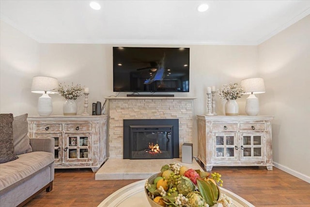 living room with dark wood-type flooring, a fireplace, and crown molding