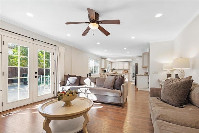 living room featuring hardwood / wood-style flooring, crown molding, ceiling fan, and french doors