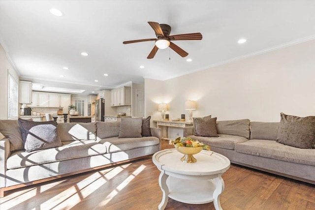 living room featuring crown molding, ceiling fan, and light wood-type flooring