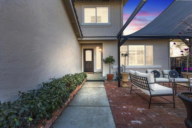 exterior entry at dusk featuring an outdoor living space and a patio