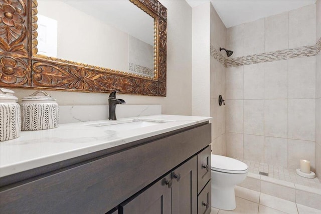 bathroom with tile patterned flooring, vanity, a tile shower, and toilet