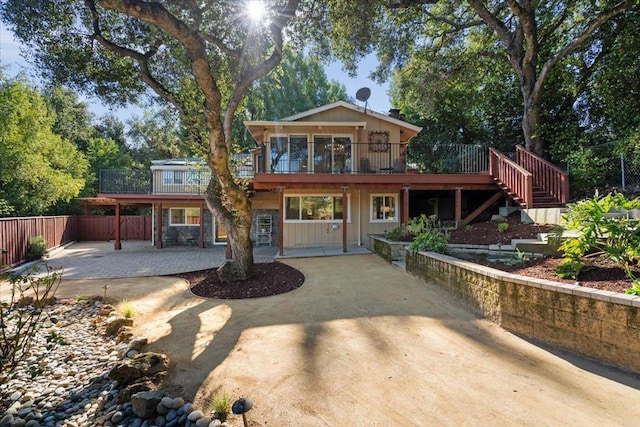 rear view of house featuring a wooden deck and a patio area