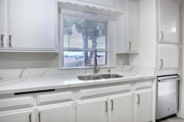 kitchen featuring light stone counters, sink, and white cabinets