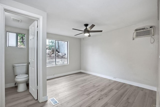 interior space with a wall unit AC, light hardwood / wood-style floors, and ceiling fan