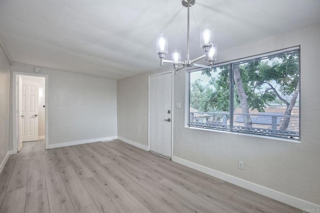 unfurnished room featuring a chandelier and light wood-type flooring