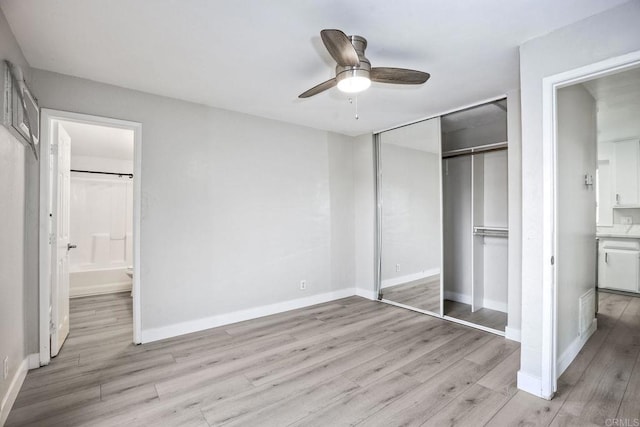 unfurnished bedroom featuring a closet, ensuite bathroom, ceiling fan, and light hardwood / wood-style flooring