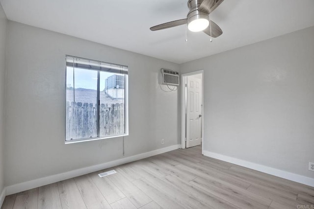 empty room featuring a wall unit AC, ceiling fan, and light hardwood / wood-style flooring