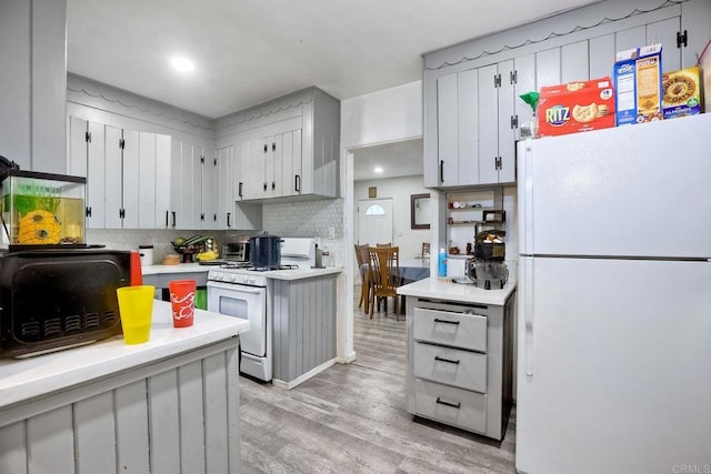 kitchen featuring white appliances, light hardwood / wood-style floors, and backsplash