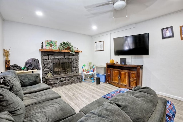 living room featuring hardwood / wood-style floors, a stone fireplace, and ceiling fan