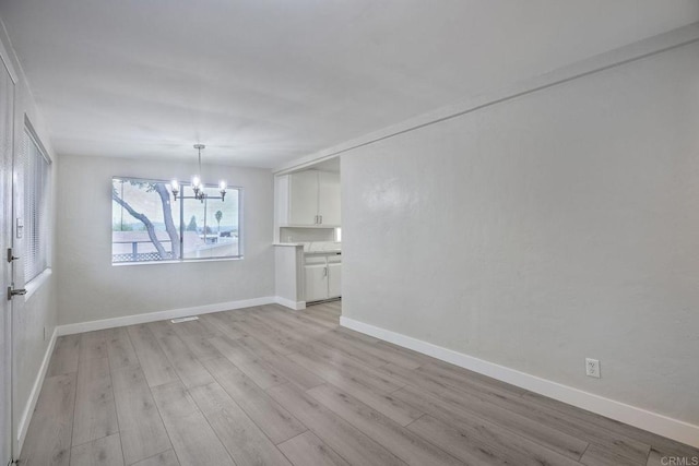 unfurnished dining area featuring an inviting chandelier and light hardwood / wood-style flooring