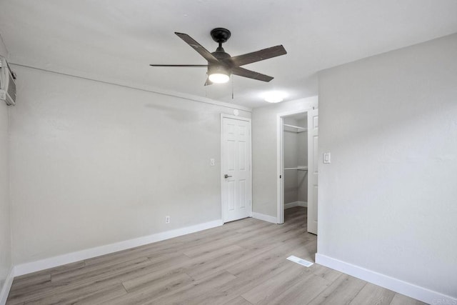 unfurnished bedroom featuring ceiling fan, a closet, a spacious closet, and light hardwood / wood-style flooring