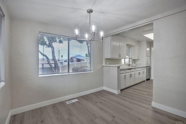 unfurnished dining area featuring sink, a notable chandelier, and light hardwood / wood-style flooring