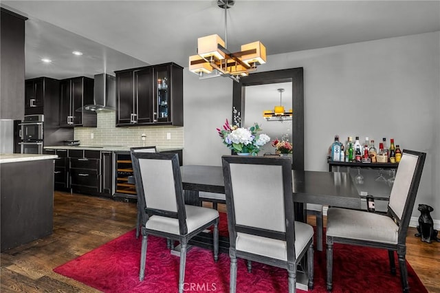 kitchen with double oven, decorative backsplash, dark hardwood / wood-style flooring, decorative light fixtures, and wall chimney exhaust hood