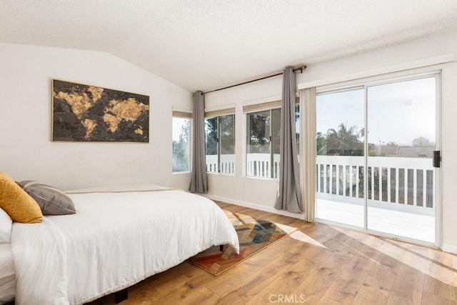 bedroom featuring lofted ceiling, access to exterior, and light hardwood / wood-style flooring