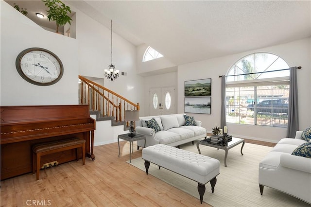 living room featuring a wealth of natural light, light hardwood / wood-style flooring, high vaulted ceiling, and a chandelier