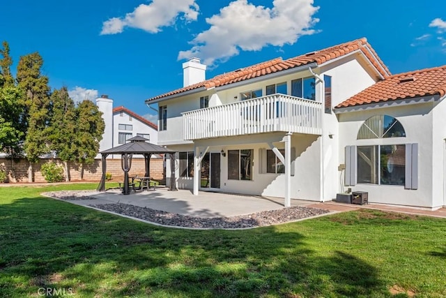 rear view of property featuring a gazebo, a balcony, a patio area, and a lawn