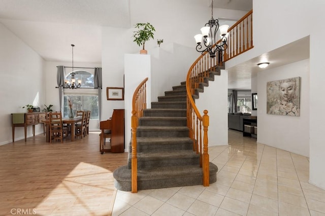 stairway featuring a healthy amount of sunlight, a high ceiling, and a notable chandelier