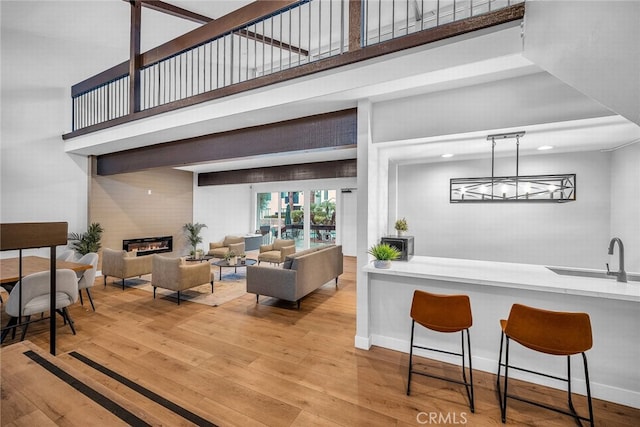 interior space with sink, an inviting chandelier, hanging light fixtures, a towering ceiling, and light hardwood / wood-style floors