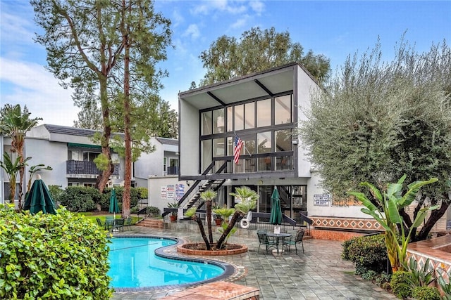 back of property featuring a community pool and a patio