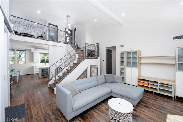 living area with dark wood-style flooring, stairway, high vaulted ceiling, and visible vents