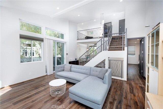 living room with a towering ceiling and dark hardwood / wood-style floors