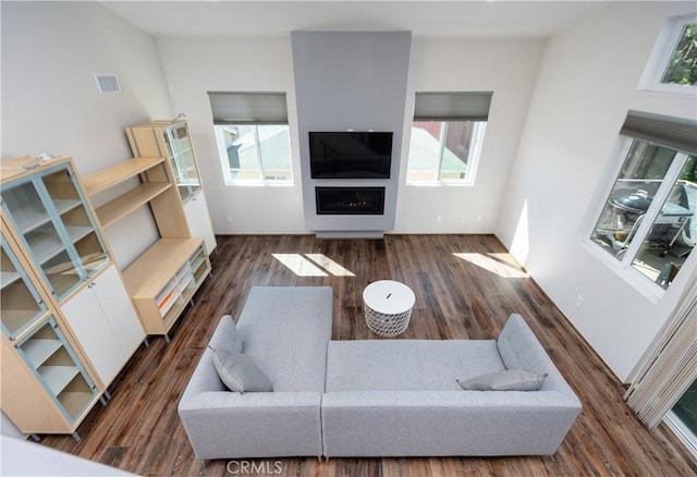 living room featuring dark wood-style floors, a fireplace, and visible vents