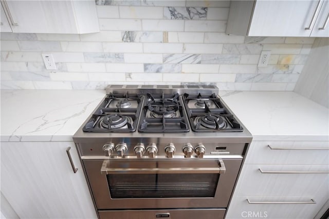 details featuring decorative backsplash, modern cabinets, light stone counters, high end stainless steel range, and white cabinetry