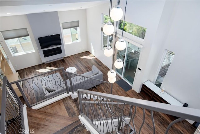 stairway with a fireplace, wood finished floors, and recessed lighting