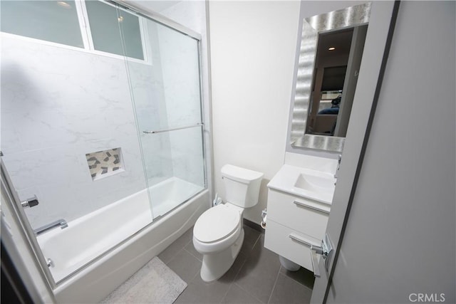 bathroom featuring tile patterned flooring, enclosed tub / shower combo, vanity, and toilet